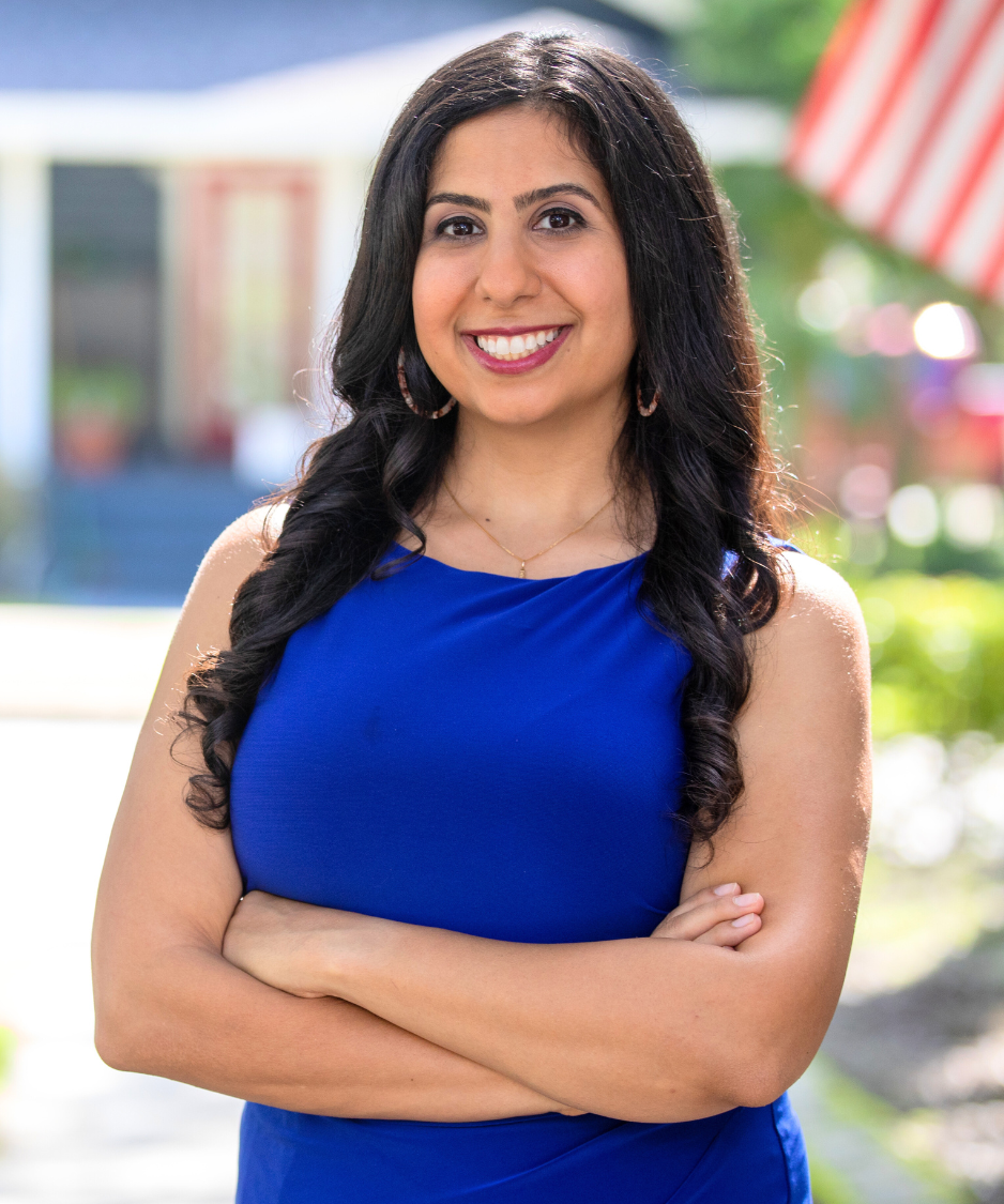Anna Eskamani standing with arms crossed in front of an American Flag