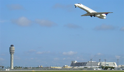 Jet flies up into the sky near a tower at Orlando International Airport