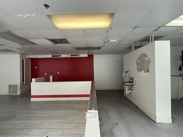 Inside of the rental space with a red painted wall in the back and a counter in the front of the wall. On the right side there is a sink and more open space.
