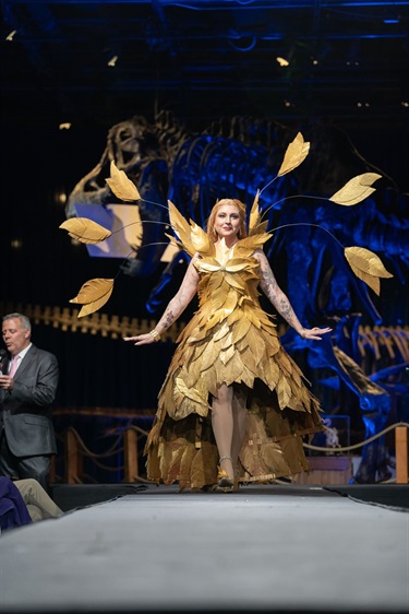 Luna Zambito models their gown made from gold-colored cardboard feathers.