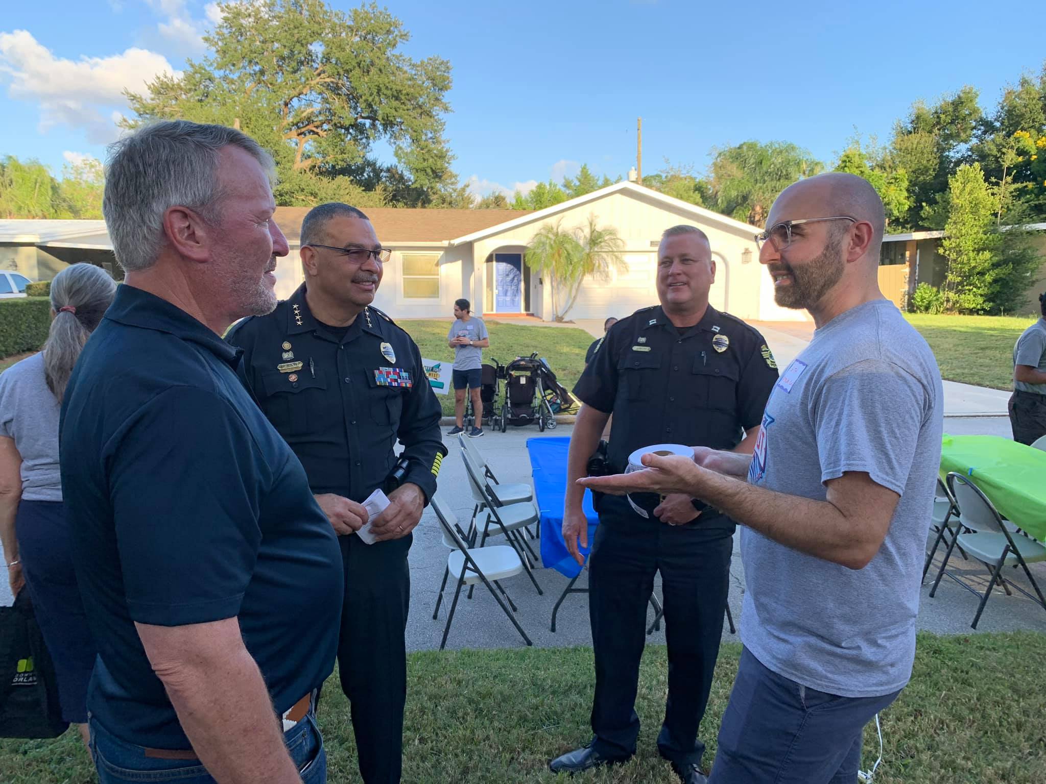 Mayor, police chief, and police officer conversing with community member