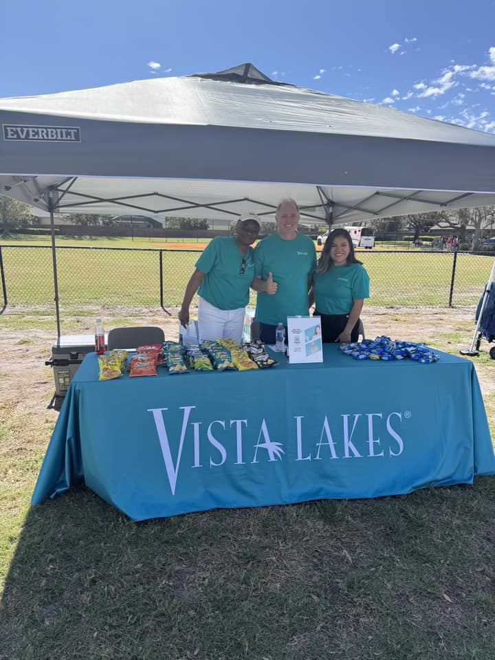 Neighborhood residents standing by a table labeled Vista Lakes with promo items