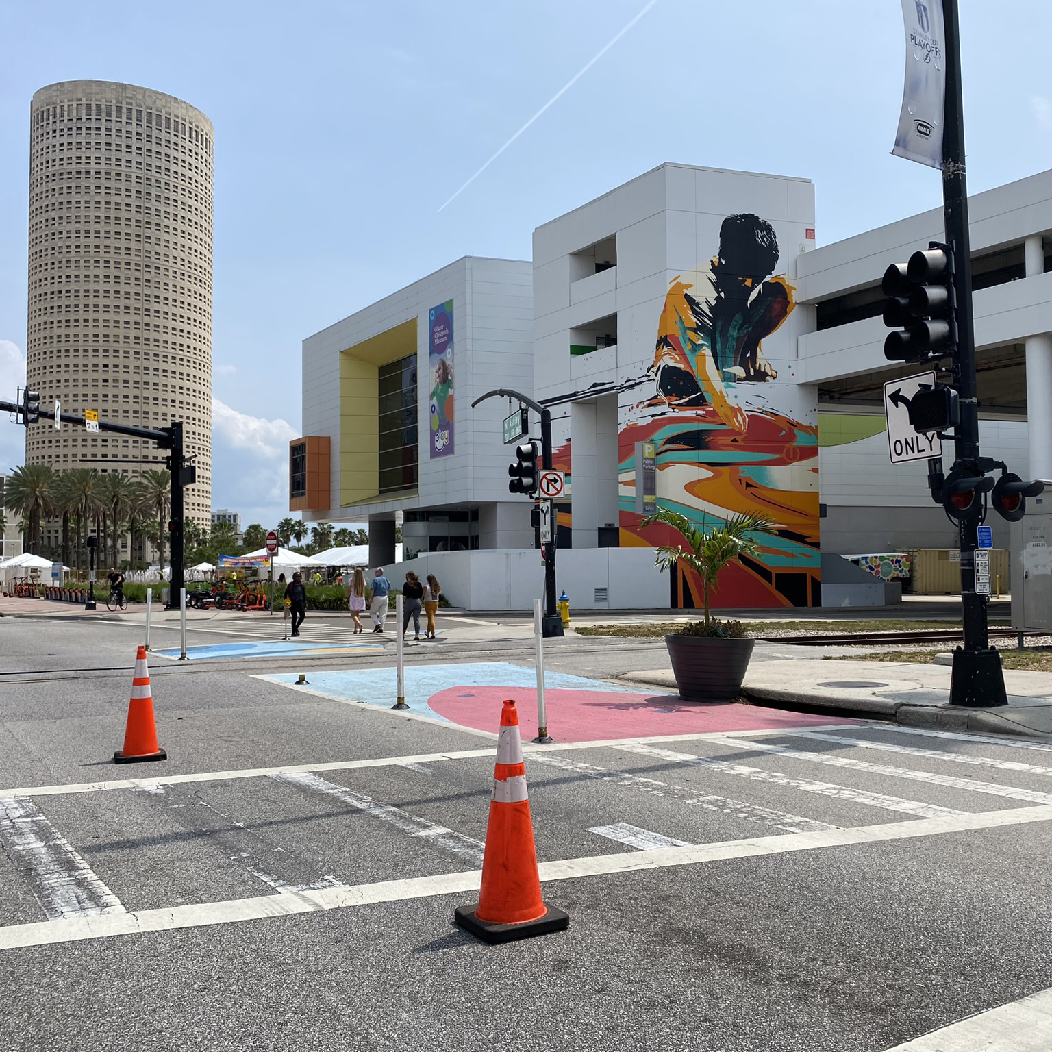 A photograph of a crosswalk adjacent to daylighting. The daylighting is delineated by flex posts and also features a small mural and a planter.
