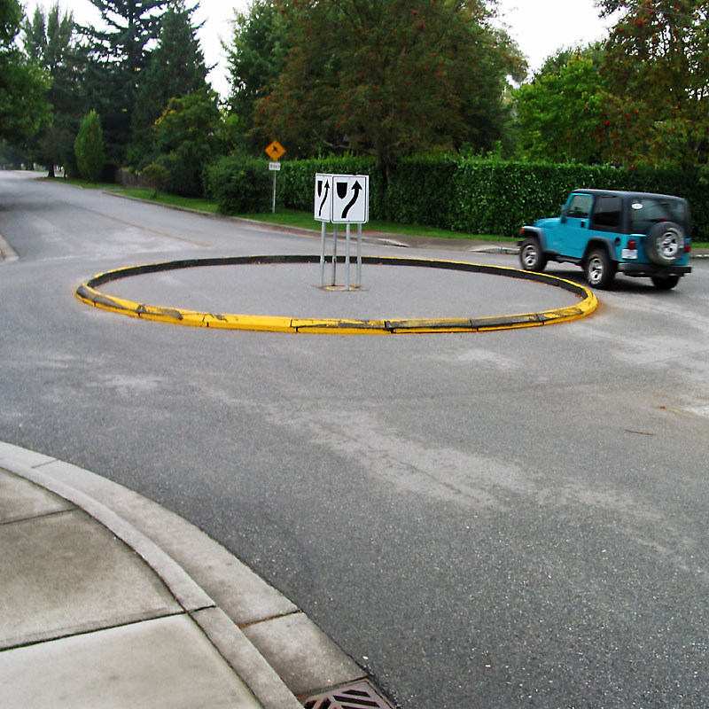 A photo of a car driving around a temporary roundabout delineated with modular curb