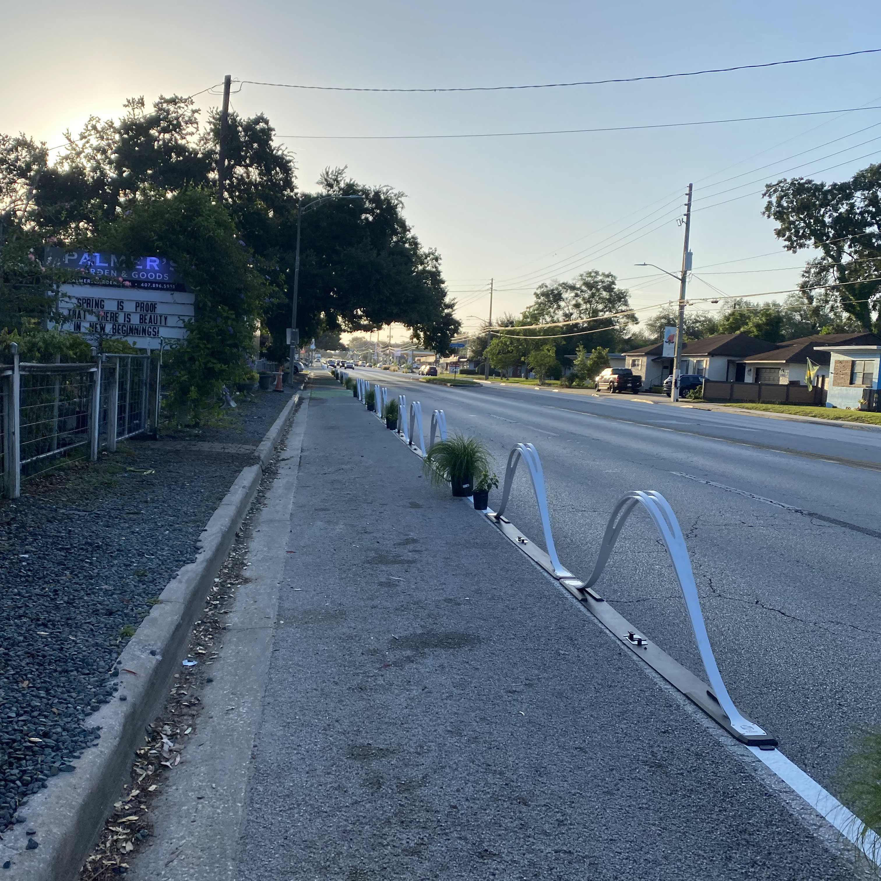 Repurposed curbside lane is lined with wave delineators and planters to mark the temporary pathway for people walking and biking.