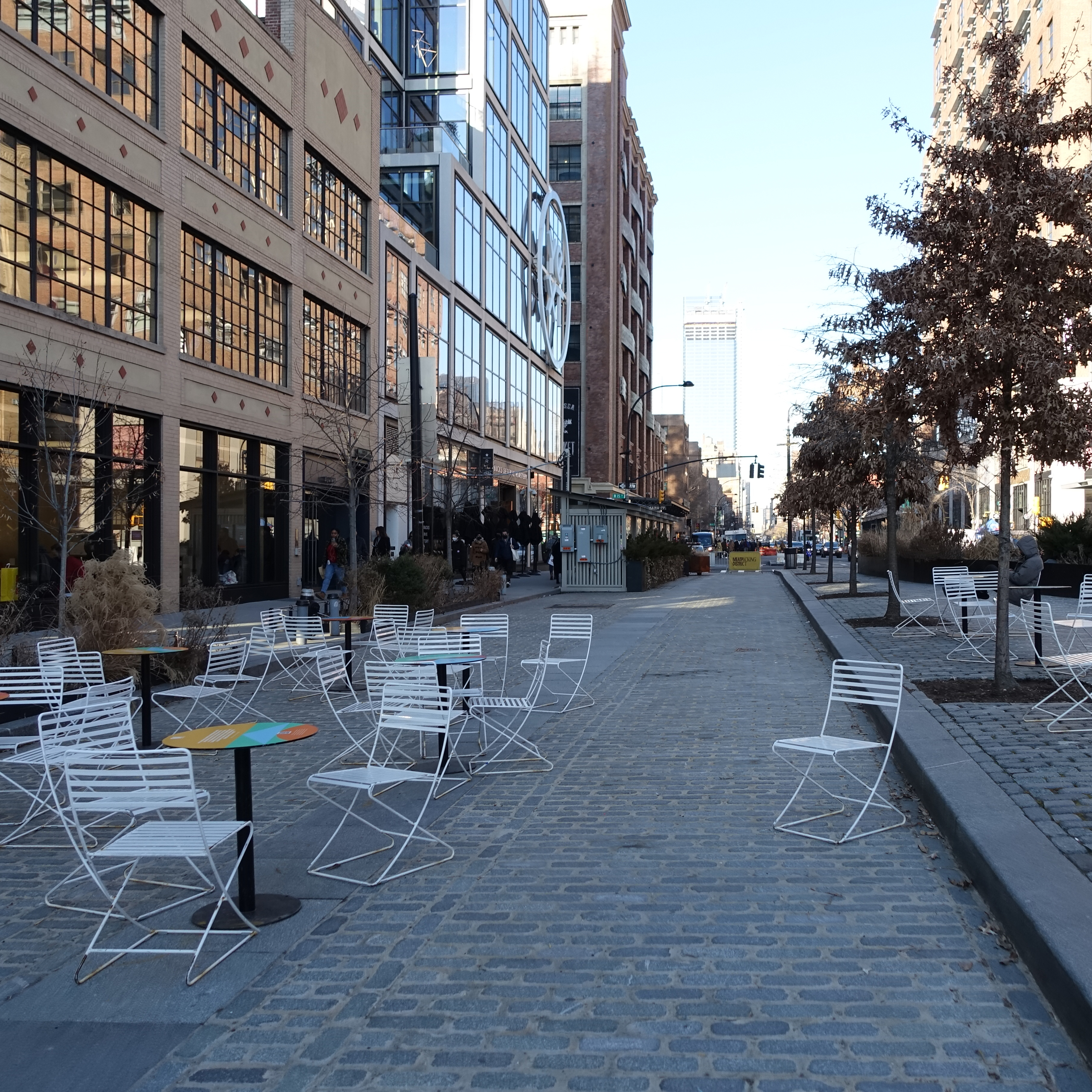 A photo of a plaza located in what was previously a street. There is street furniture and plantings.