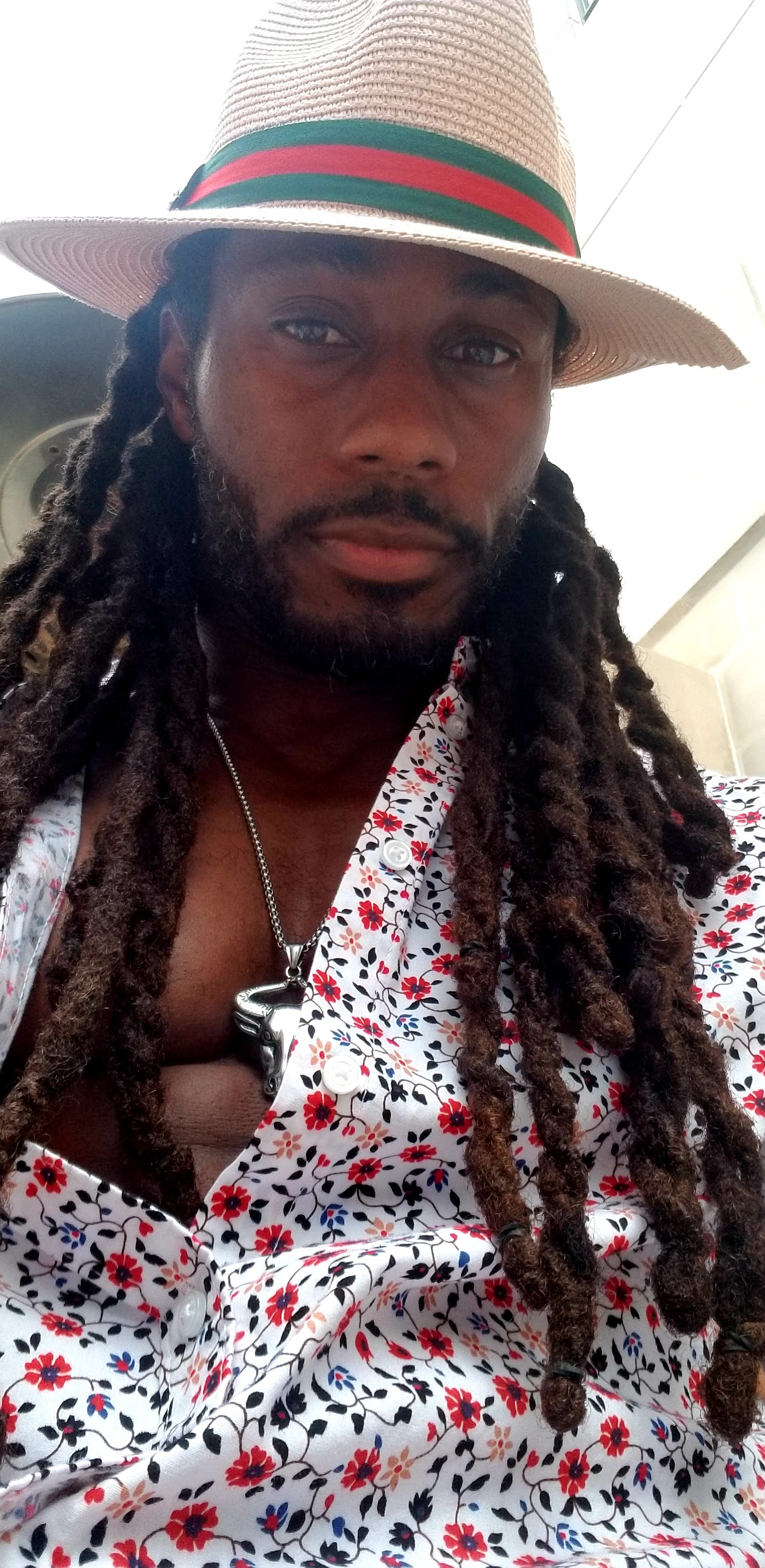 Terance Jones is wearing a white shirt with read and blue flowers and a straw hat