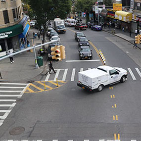 A photo of an corner with a slow-turn wedge and left-turn hardening marked by yellow striping and flex posts.