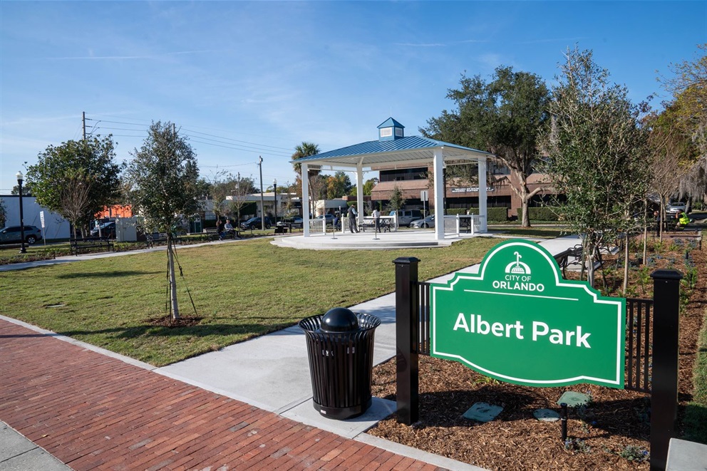 Two individuals stand under a gazebo on the day of the Albert Park ribbon cutting ceremony. A sign reading 'City of Orlando Albert Park' is visible in the bottom right corner.